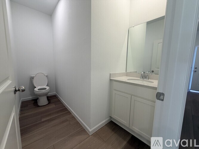 A bathroom with a toilet, sink, and wooden floors.