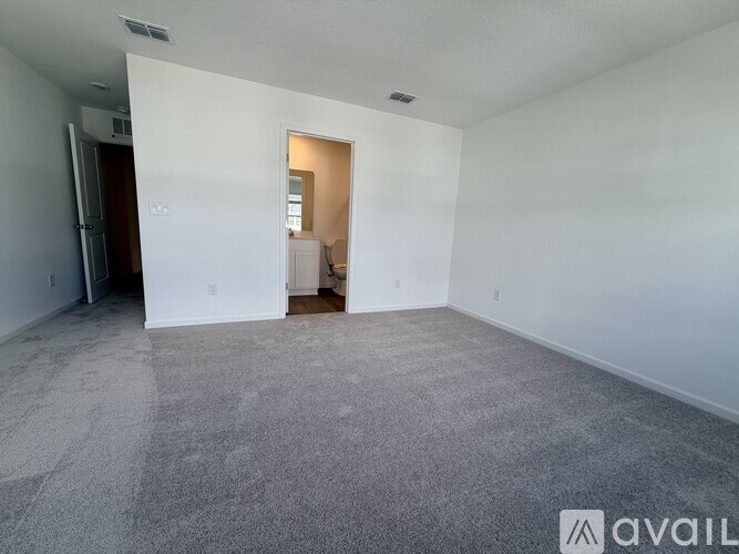 A spacious room with a carpeted floor and a doorway leading to another room.