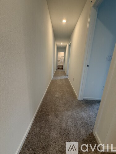 A long hallway with carpeted floors and white walls.