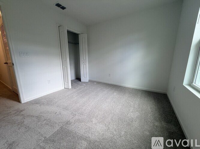 A room with a carpeted floor and a doorway leading to another room.