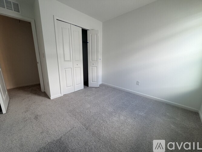 A carpeted room with a door and a wall socket.
