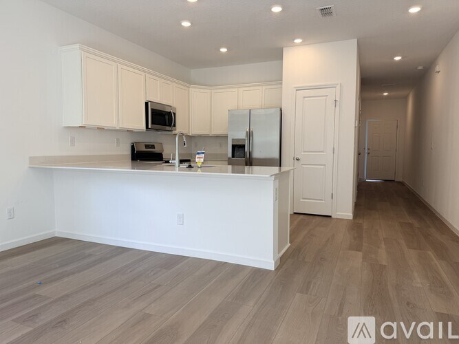A kitchen with white cabinets and a wooden floor.