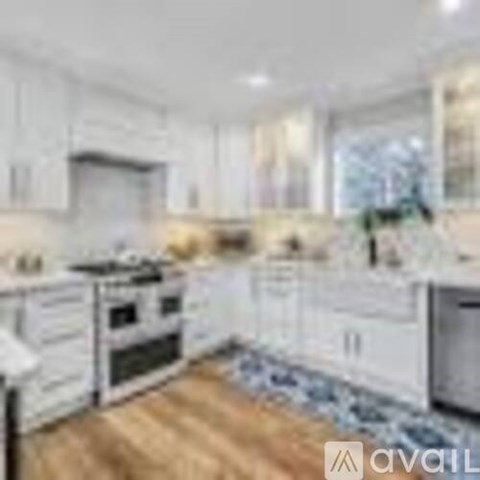 A kitchen with white cabinets and a wooden floor.
