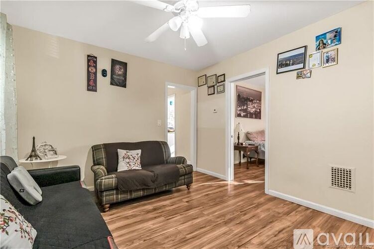 A living room with a couch, a fan, and pictures on the wall.