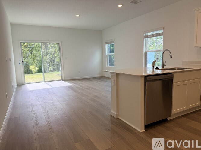 A spacious kitchen and living room with wooden flooring and white walls.