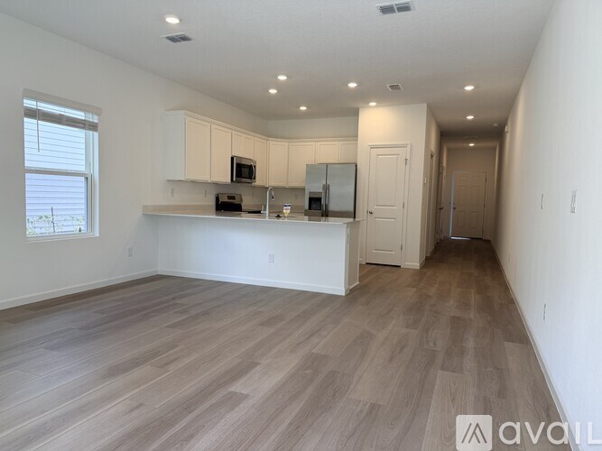 A kitchen area with wooden flooring and white walls.