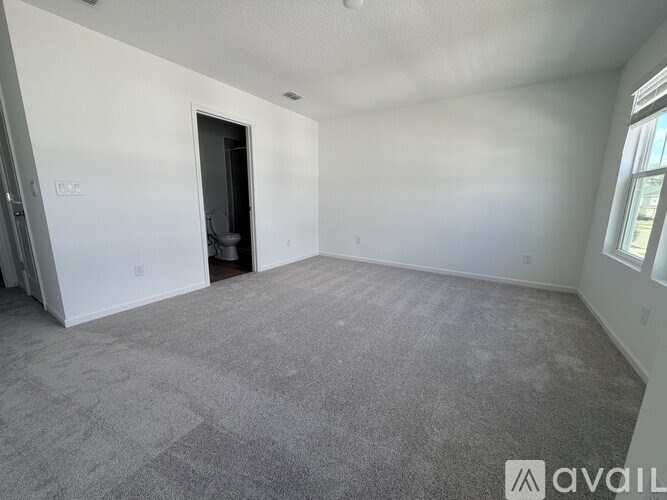 A spacious room with a carpeted floor and a doorway leading to another room.