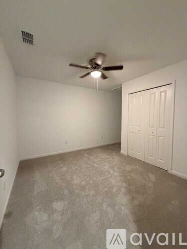 A room with a carpeted floor and a window letting in light.