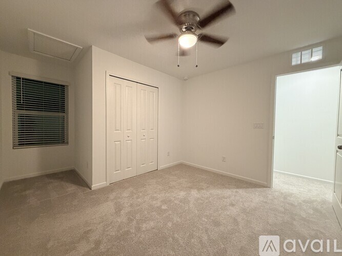 A carpeted room with a door and a wall socket.
