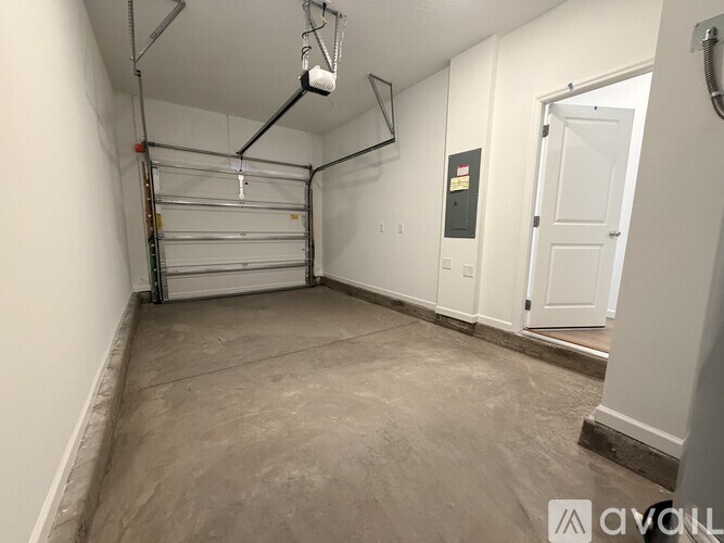 A spacious garage with a white door and a grey floor.
