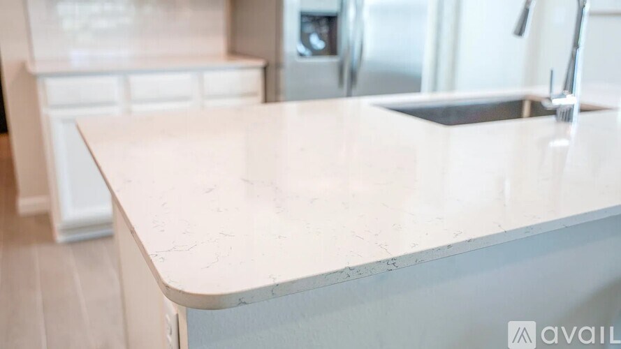 A white kitchen countertop with a sink and a faucet.