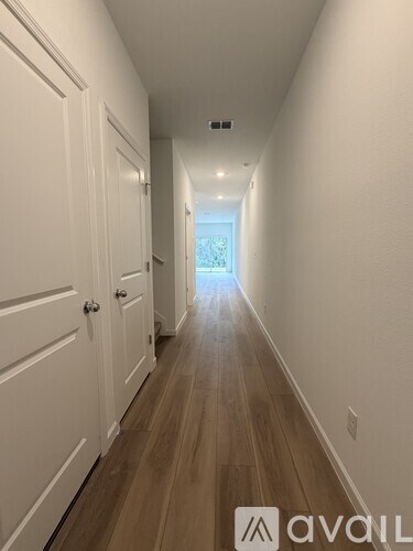 A long hallway with white doors and wooden floors.