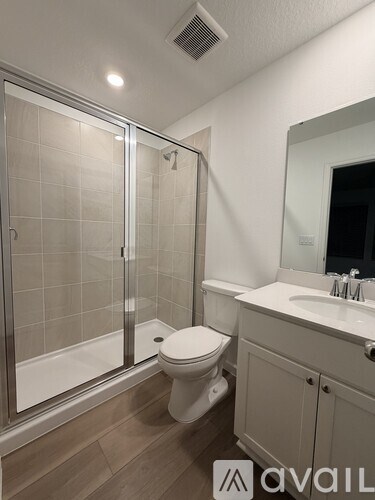 A bathroom with a toilet, sink, and wooden floors.