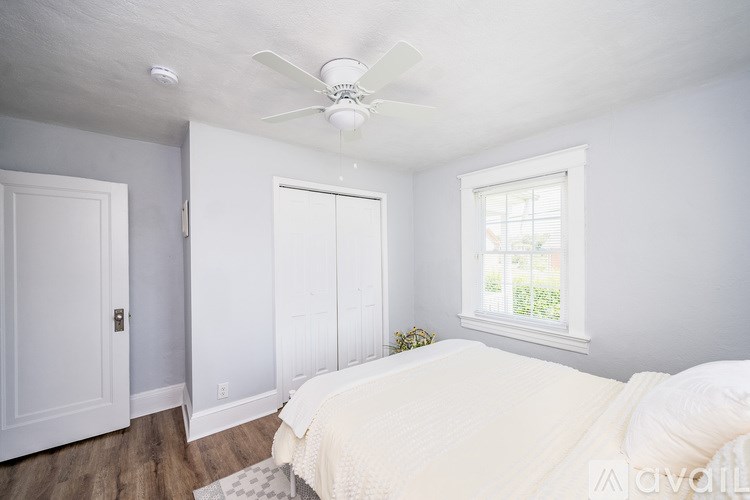 A bedroom with a bed, a window, and a ceiling fan.