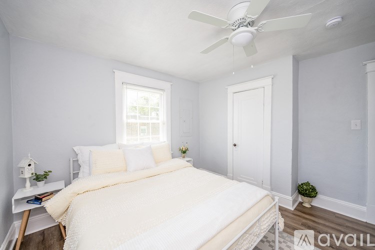 A bedroom with a bed, a fan, and a window.