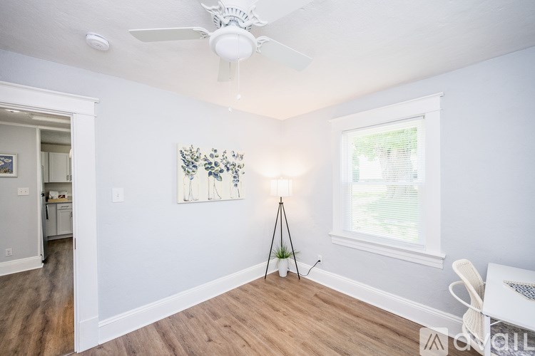 A room with a ceiling fan and a painting on the wall.