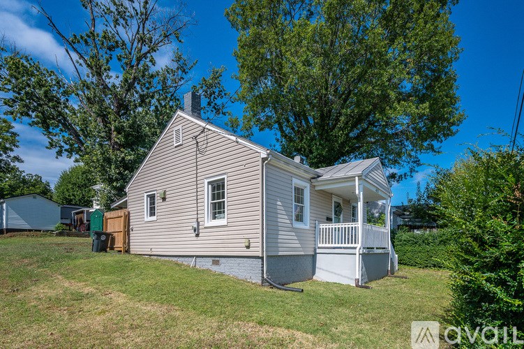 A gravel driveway leads to a house with a large tree in the yard.