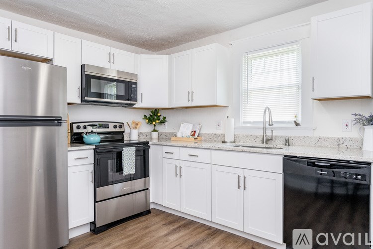 A kitchen with white cabinets and a black dishwasher.