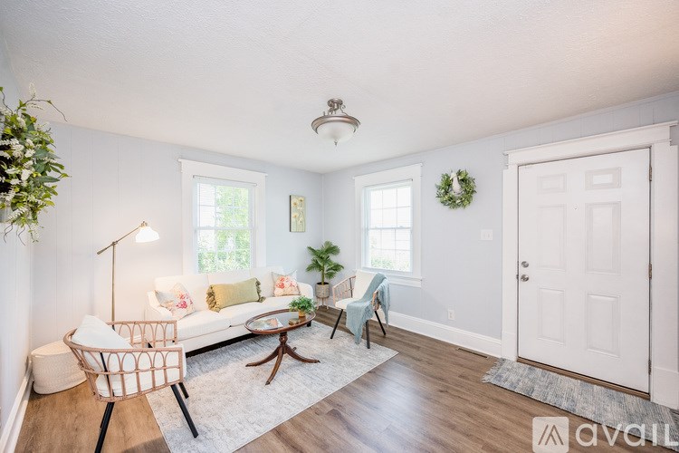 A living room with a white couch, a wooden coffee table, and a white chair.