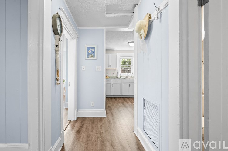 A living room with a white couch, a wooden chair, and a rug.