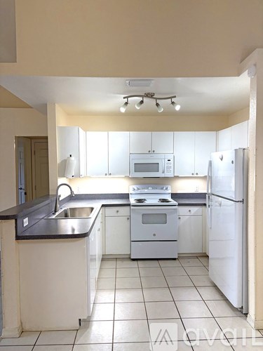 A kitchen with white appliances and a black counter.