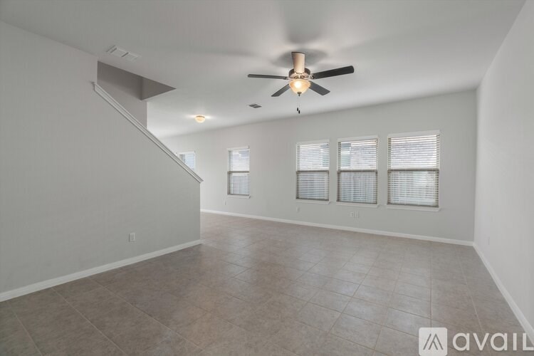 A spacious room with a ceiling fan and tiled flooring.