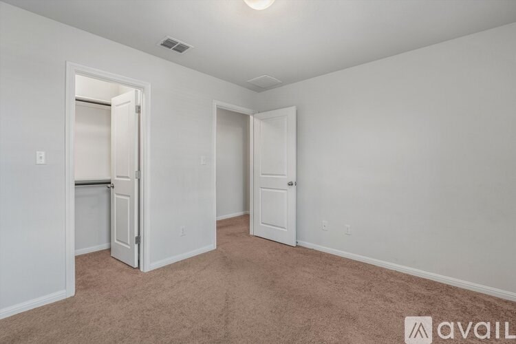 A room with carpeted floor and two doors.