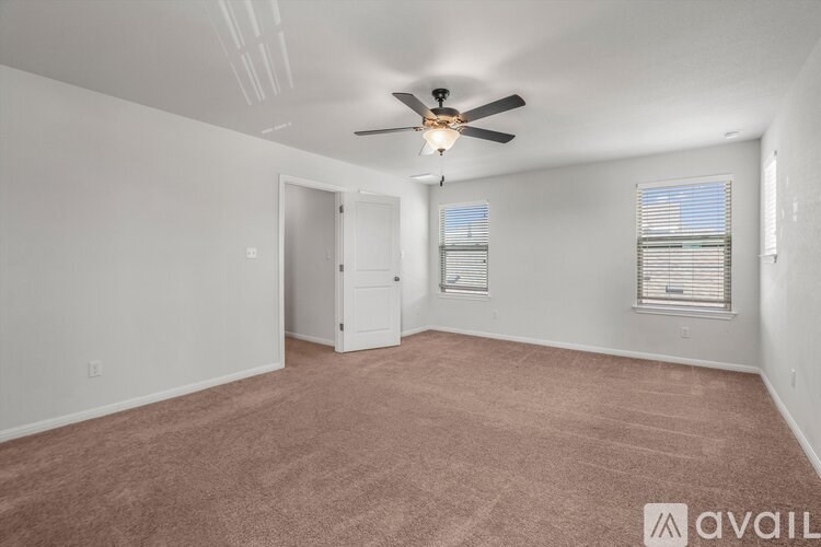 A room with a ceiling fan and carpeted floor.