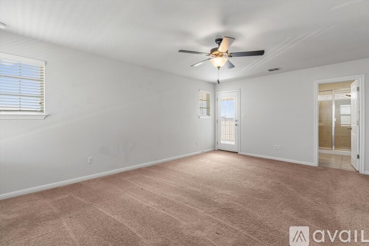 A room with a ceiling fan and carpeted floor.