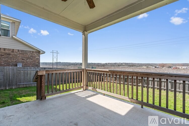 A patio with a wooden railing and a concrete floor.