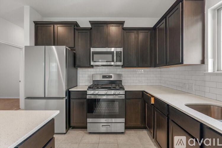A kitchen with dark brown cabinets and stainless steel appliances.