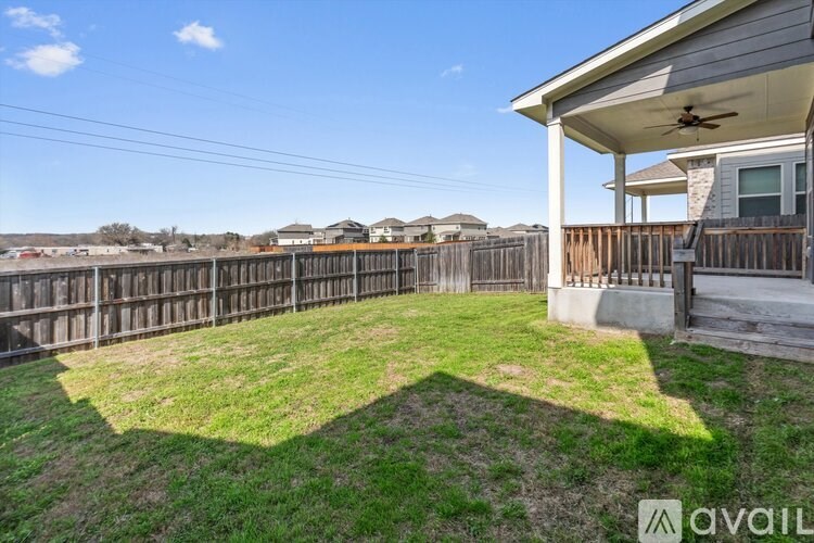 A backyard with a wooden fence and a house with a balcony.