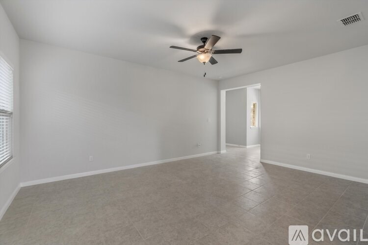 A spacious room with a ceiling fan and tile flooring.