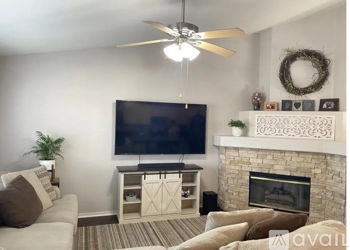 A living room with a fireplace, television, and a ceiling fan.