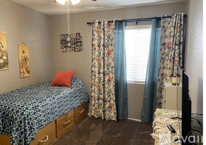 A bedroom with a bed, curtains, and a painting on the wall.