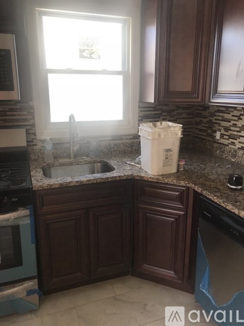 A kitchen with brown cabinets and a white trash bag on the counter.