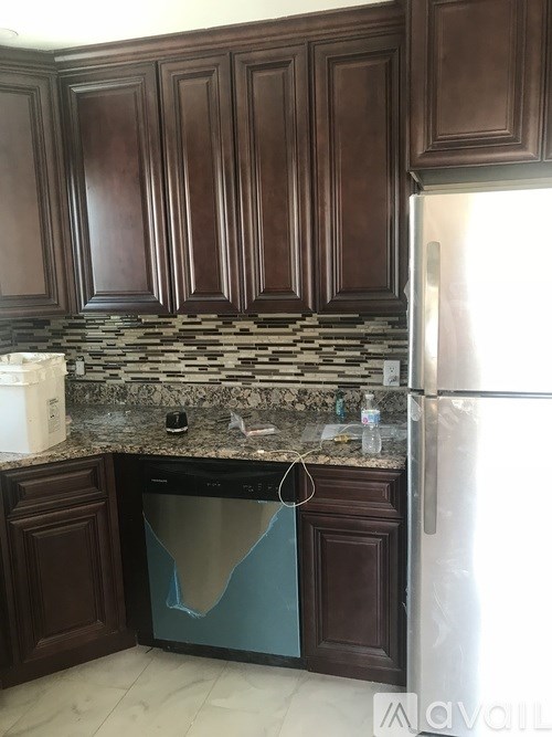 A kitchen with brown cabinets and a stainless steel refrigerator.