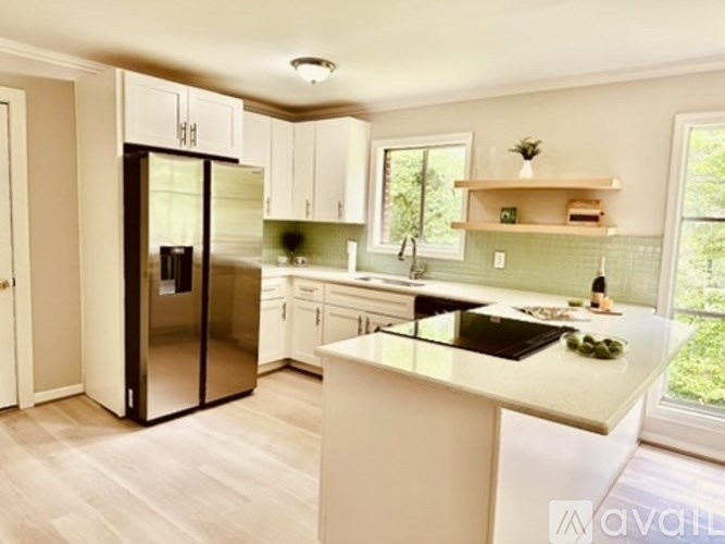 A kitchen with white cabinets and a black fridge.