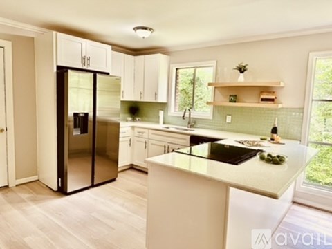 A kitchen with white cabinets and a black fridge.