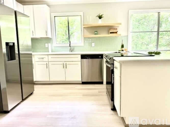 A kitchen with white cabinets and a wooden floor.