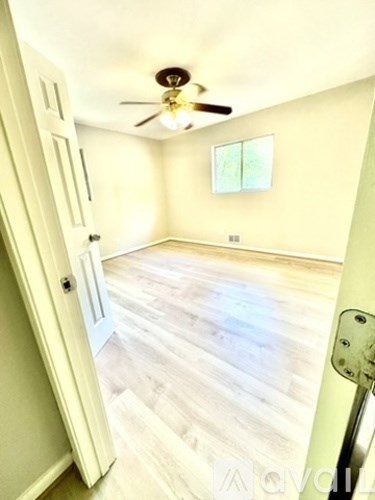 A room with a ceiling fan and a door.