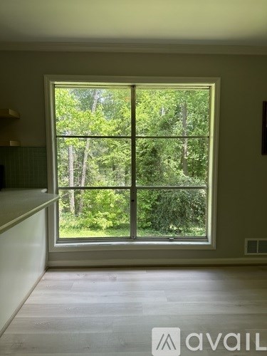 A room with a large window that has a view of trees.