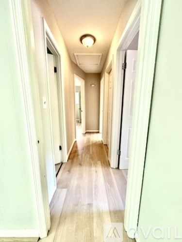 A long hallway with white doors and a light on the ceiling.