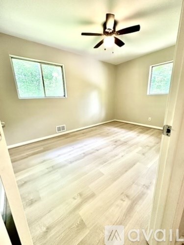 A room with wooden flooring and a ceiling fan.