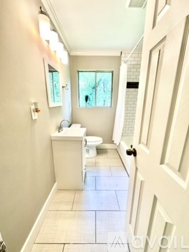 A white bathroom with a toilet, sink, and a window.