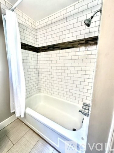 A white bathtub with a shower curtain in a bathroom with white tiles.