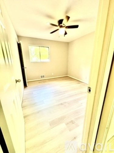 A room with a ceiling fan and wooden flooring.
