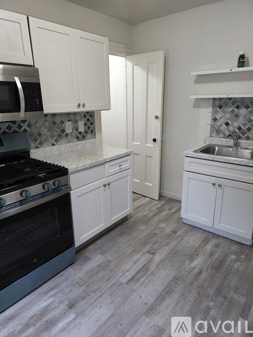 A kitchen with white cabinets and a black stove top oven.