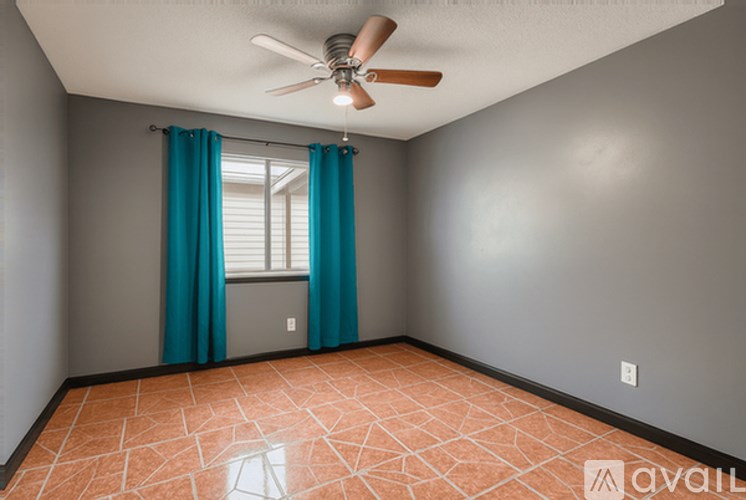 A room with a ceiling fan and a window with blue curtains.
