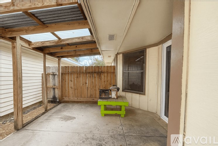 A wooden bench with a green cushion is in the middle of a patio area.